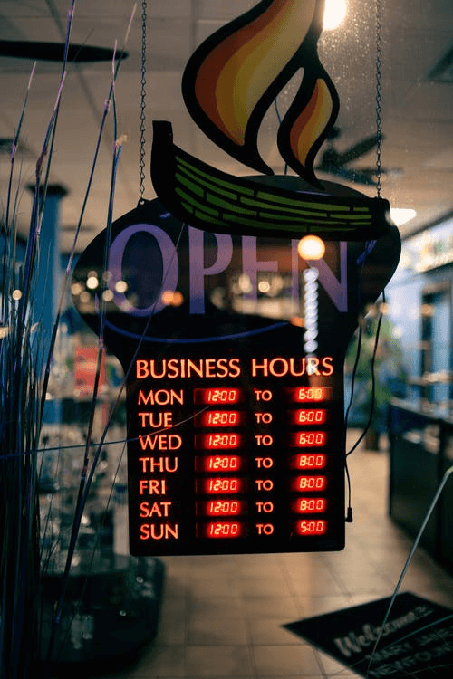 A signboard outside a store displaying business hours.